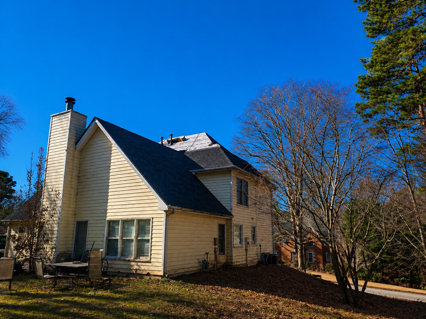 Crew installing new roofing shingles on residential home